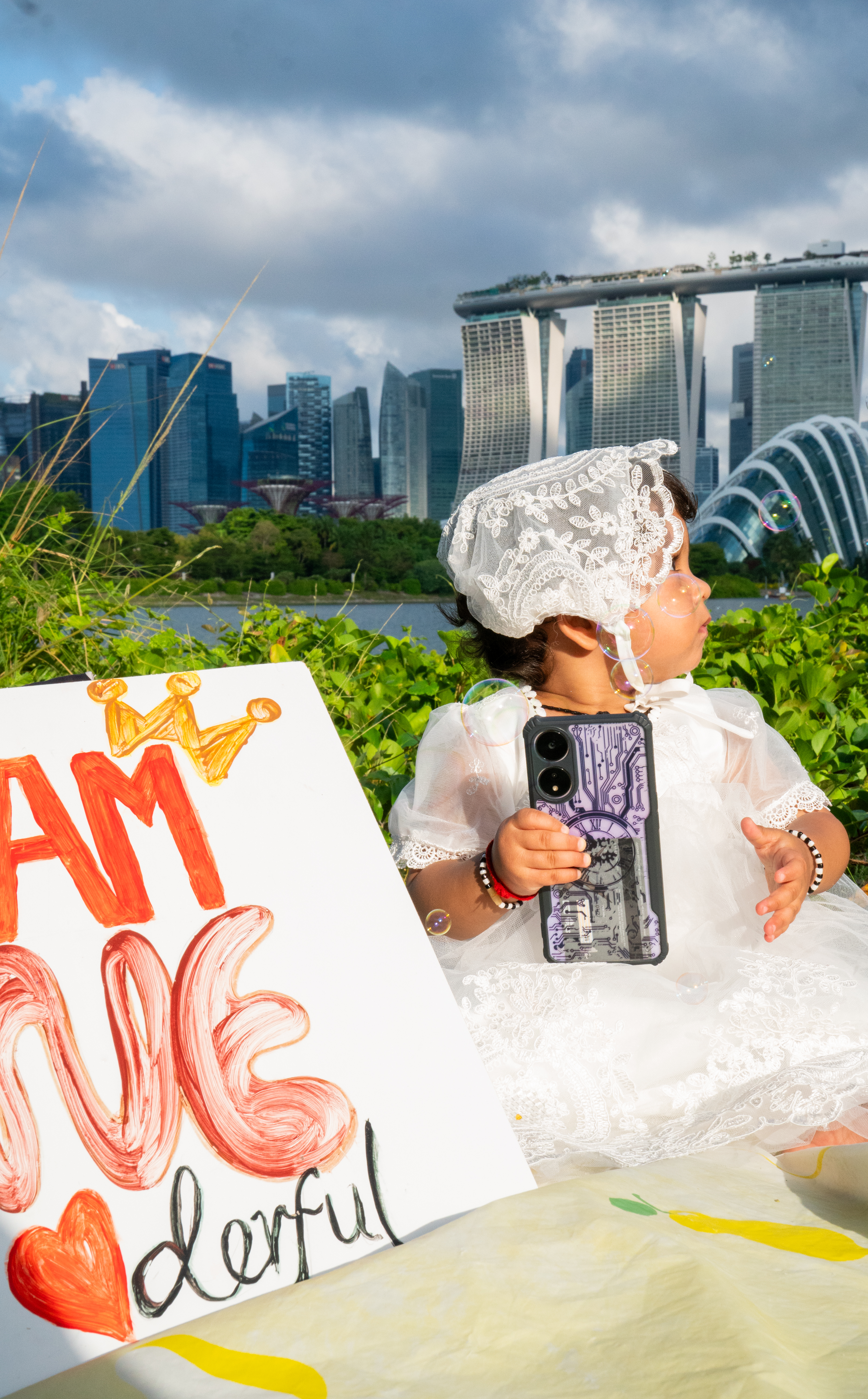 Baby in white dress holding phone
