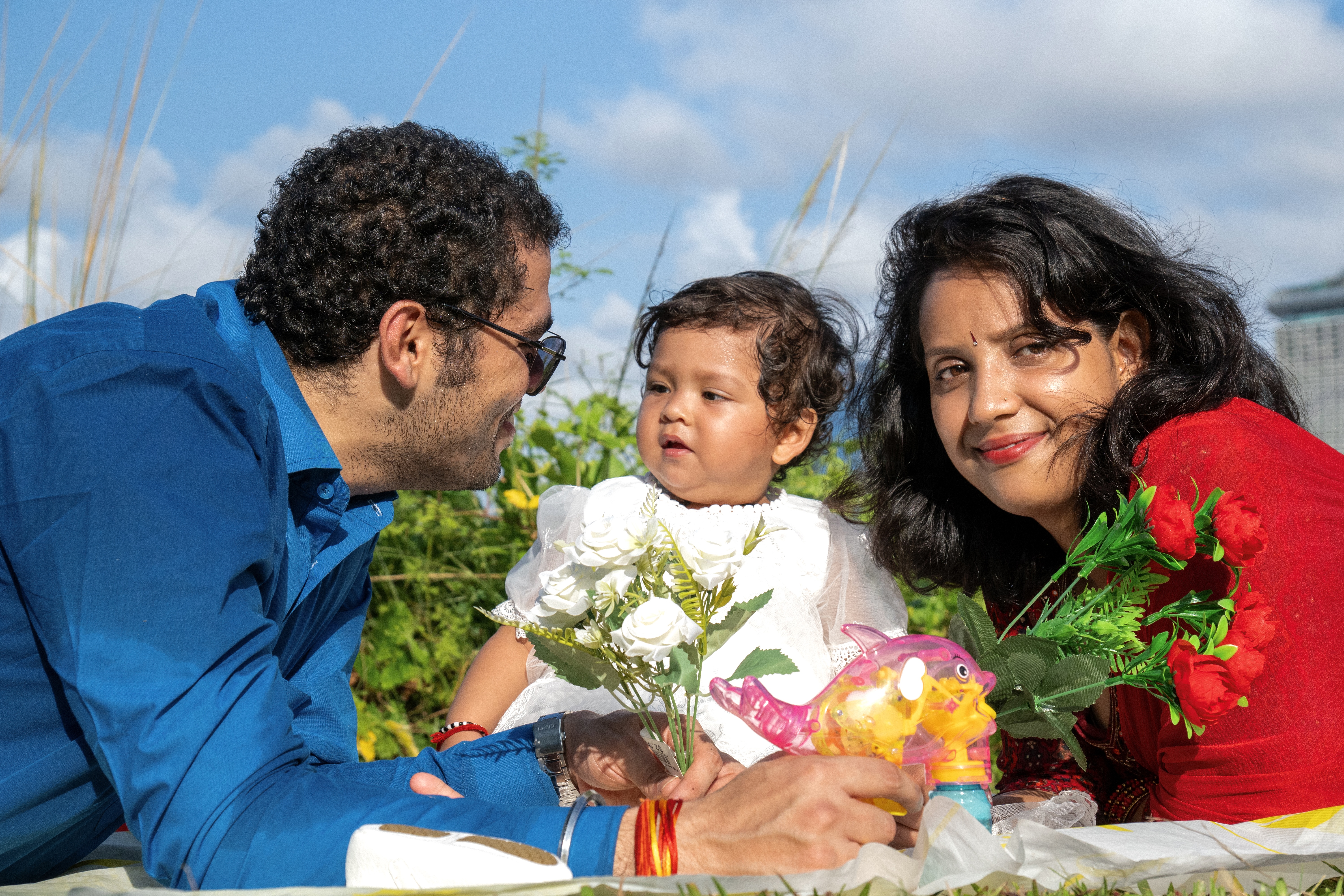Family with baby in white dress and flowers