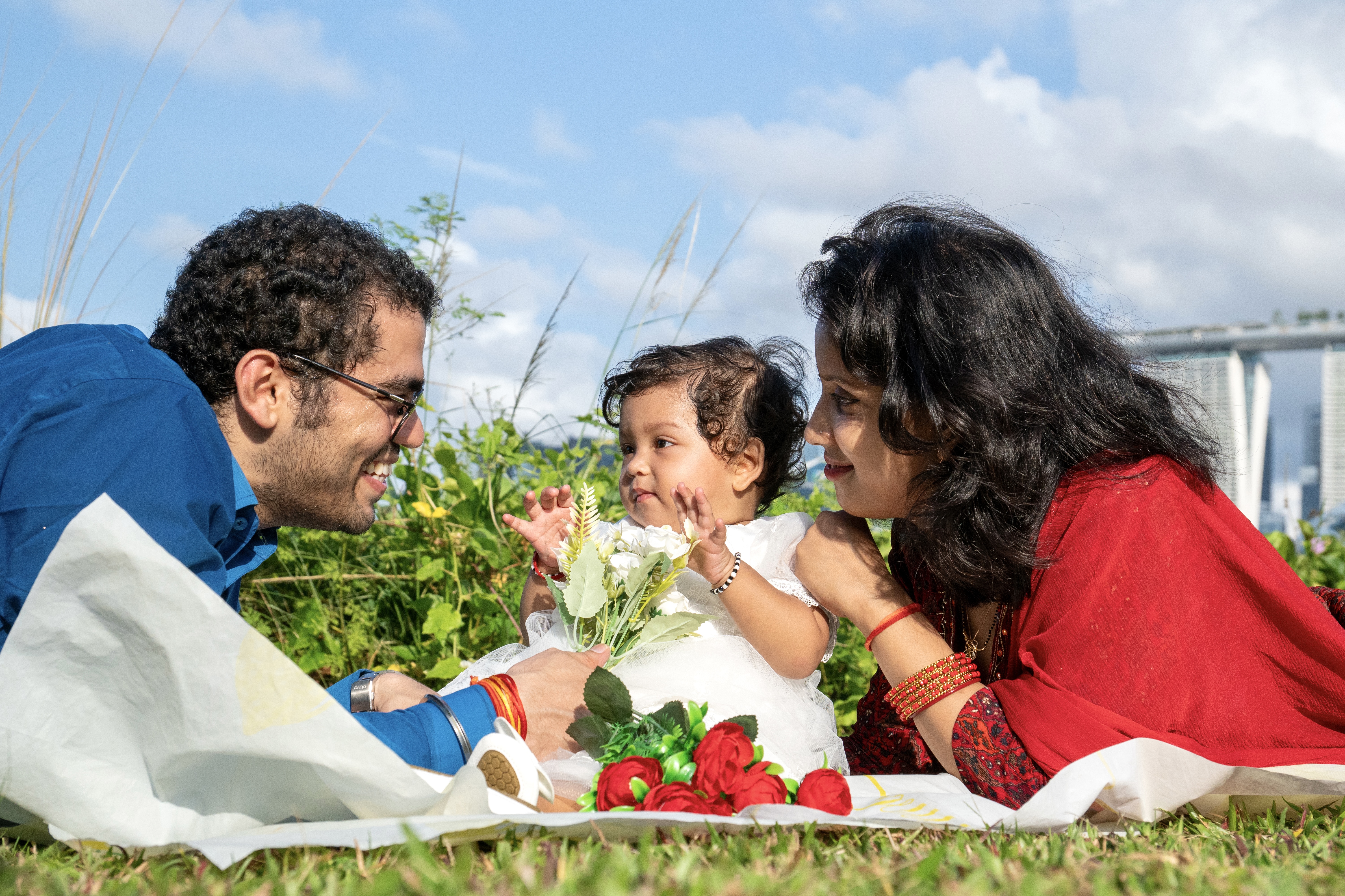 Family with baby in white dress having picnic outdoors