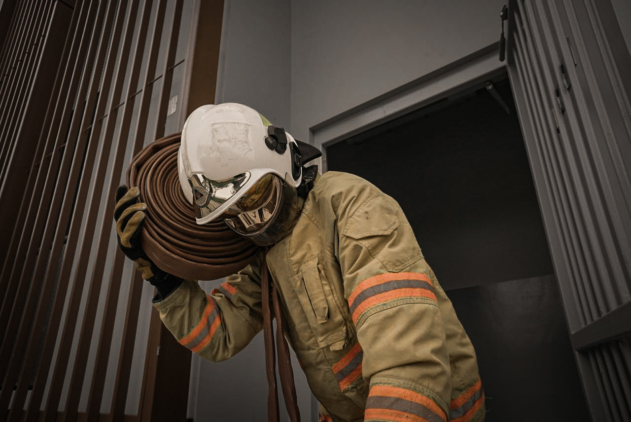 Firefighter carrying hose exiting building
