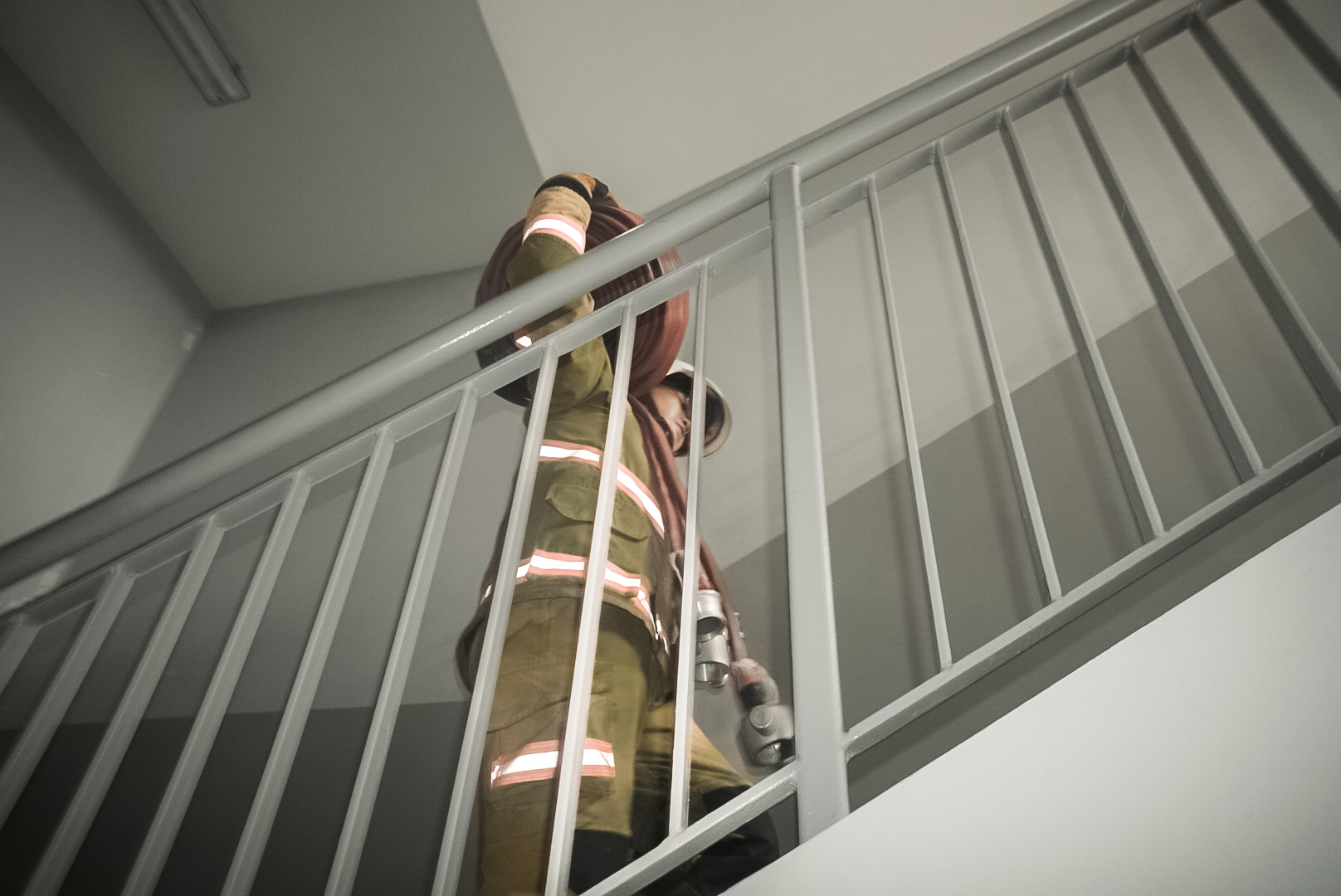 Firefighter carrying hose on stairs